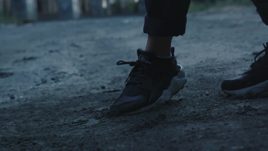 A person with sneakers dancing on dirt and rocks
