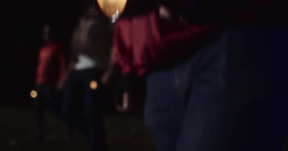 Three men are walking in the woods with flashlights