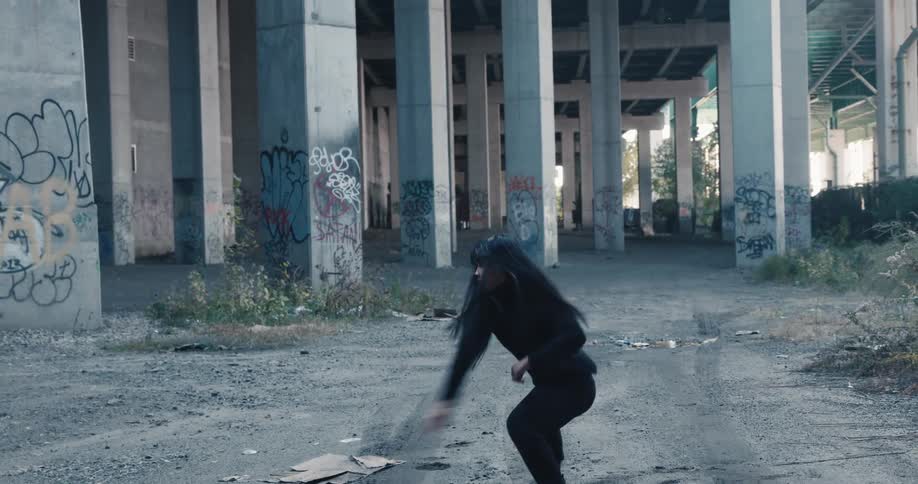 Woman dances near graffiti covered columns