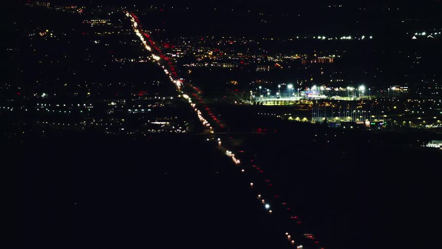 Vast traffic on the I-5 interstate in this high altitude aerial at night as white and red lights can be seen streaming into and out of Portland Oregon