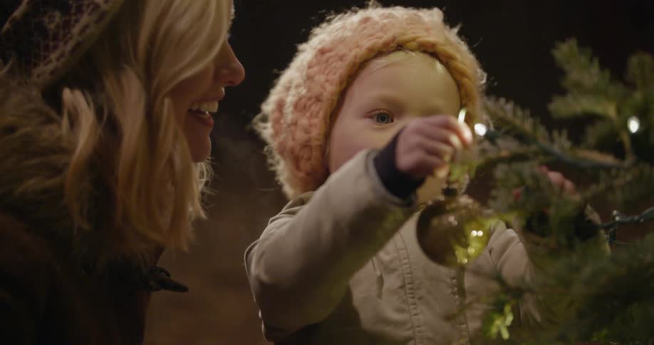 A woman and baby decorate a christmas tree