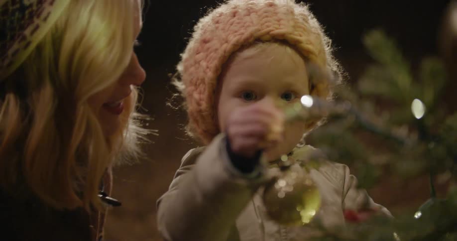 Woman and child hanging an ornament on a christmas tree before it falls