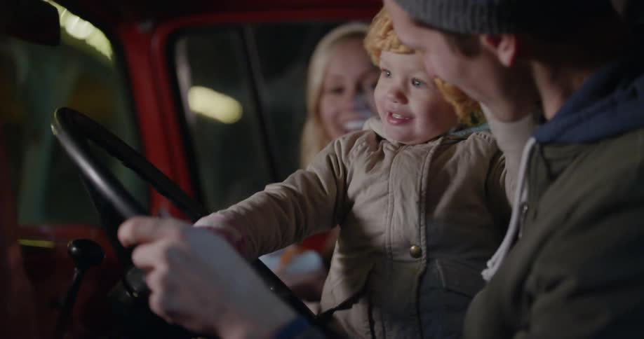 A man woman and child sit in the front of a pickup truck