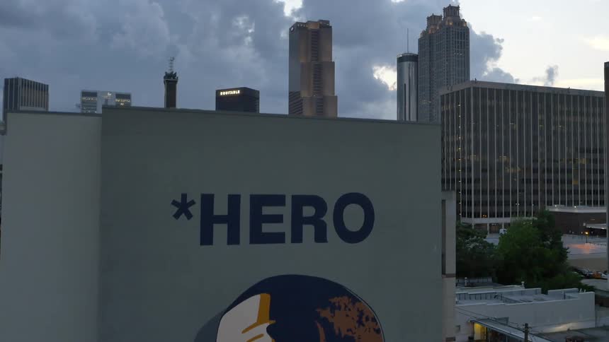 A building has a painting of a man with the word heroes as it raises up above showing a city