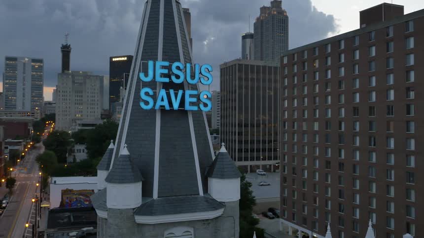 Moving past a city with a building that says jesus saves