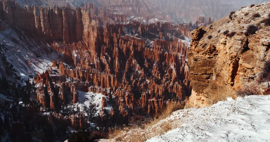 A light layer of snow sits atop the rocky slopes of an enormous canyon