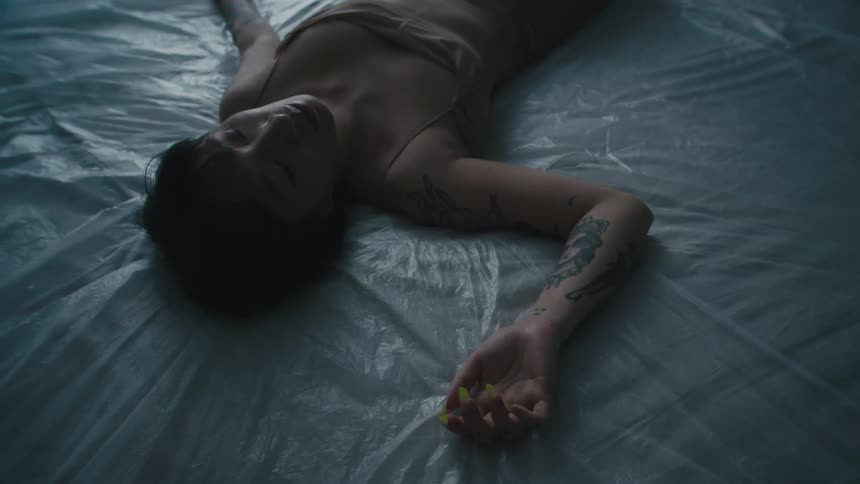 A woman lies down on a mattress covered with a plastic tarp