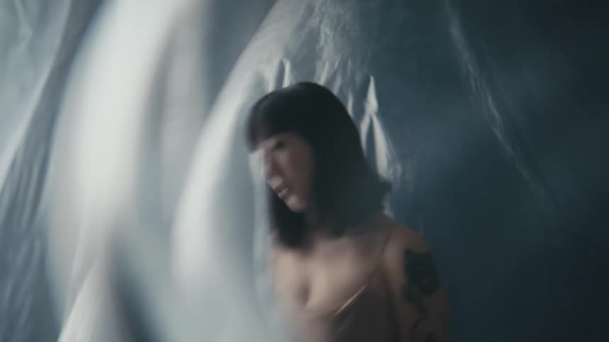 A woman poses in front of a blowing white sheet