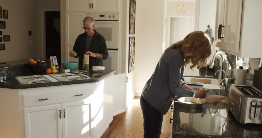 A man and woman stand in a kitchen as they prepare food to cook