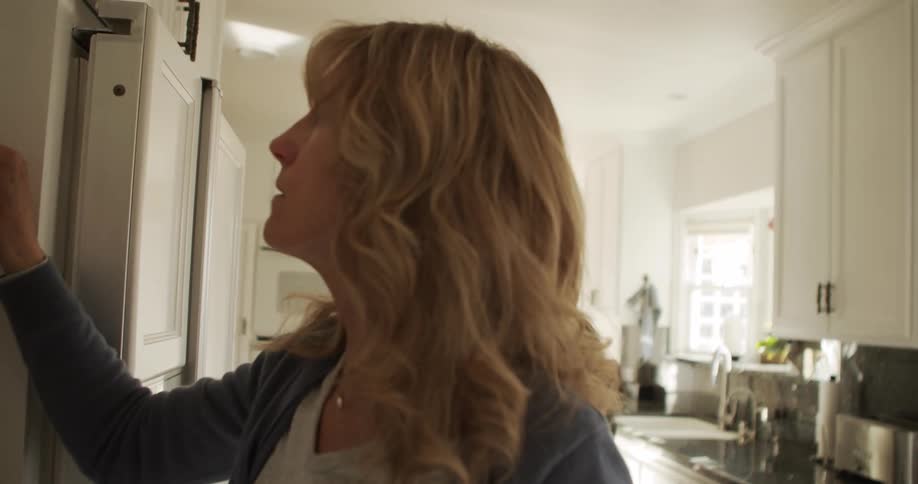 A woman puts a measuring cup in the microwave as her husband rummages through their fridge