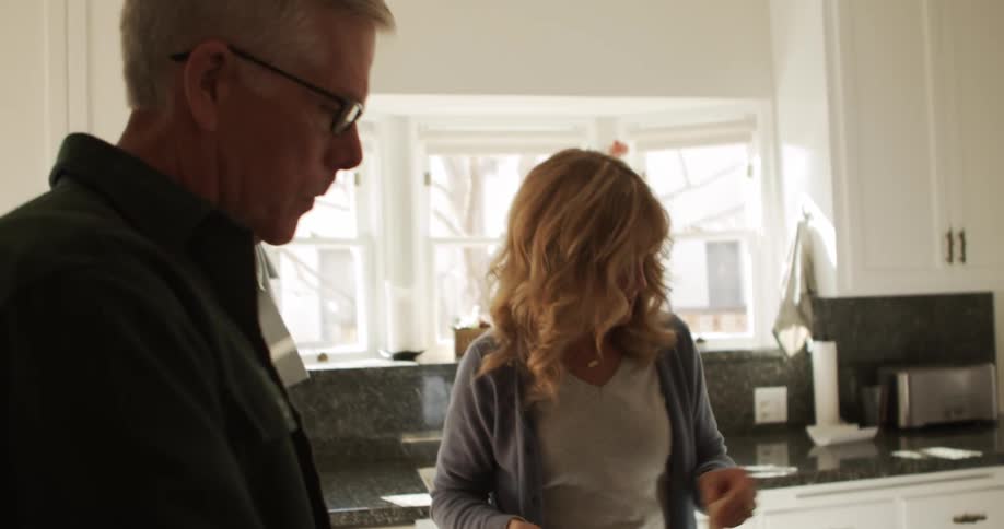 A man and woman stand in a kitchen where they prepare to mix ingredients in a bowl