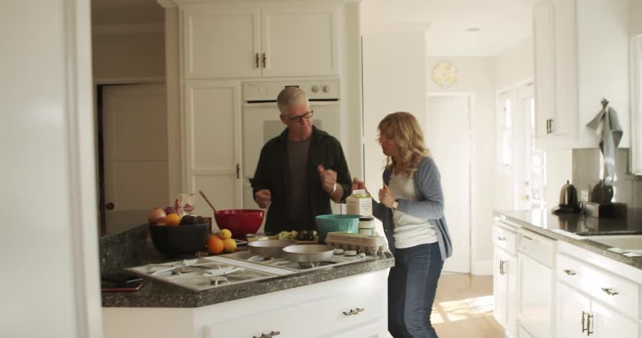 A man and a woman in a kitchen dancing with cabinets in the background