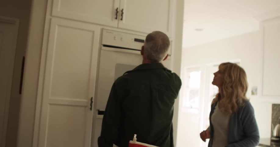Couple puts cake pans in oven before entering settings and consulting tablet