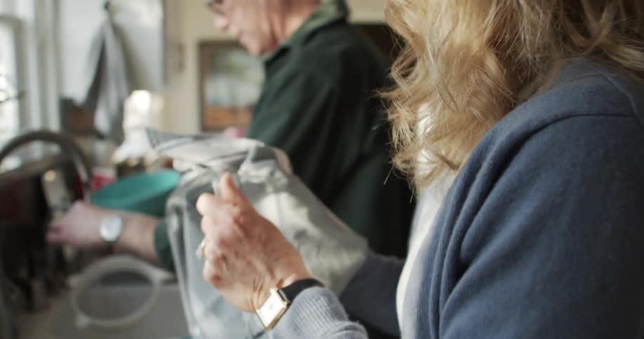 A man and woman do dishes together at home