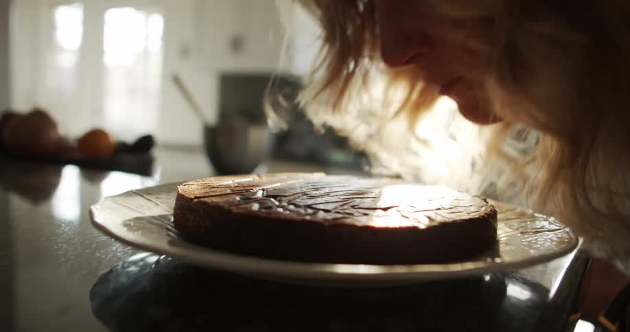 A woman bends down and smells some food at home