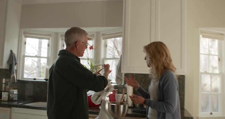 A man and woman both taste the chocolate frosting that they just prepared