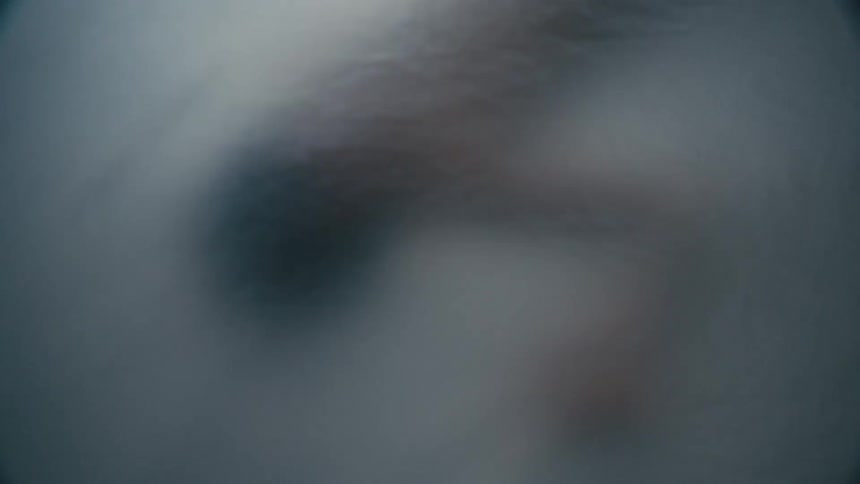 A woman in a room laying on a bed and being covered with plastic