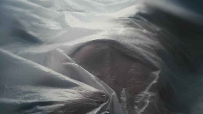 A woman in a room laying on a bed with a plastic sheet covering her