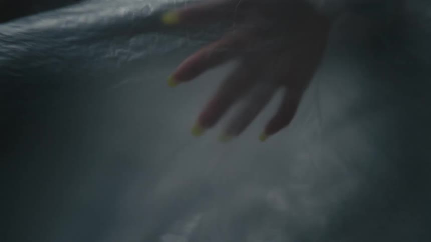 A womans hand moving under a sheet of plastic