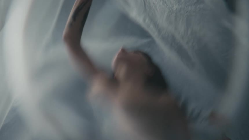 A naked woman moves under a plastic sheet