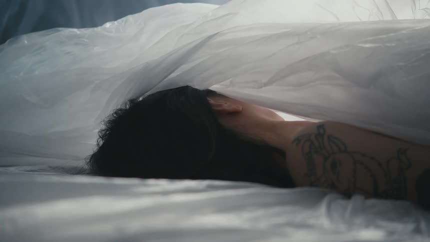A woman laying as a blanket covers her