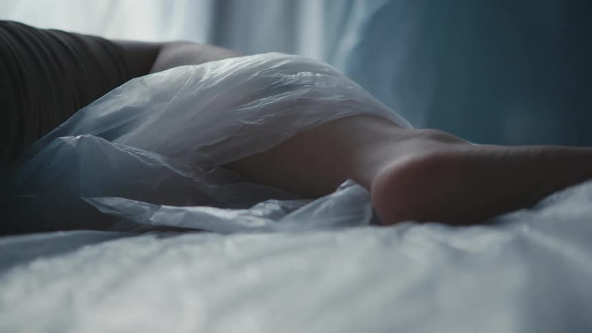A plastic tarp wraps around a womans leg as she sleeps