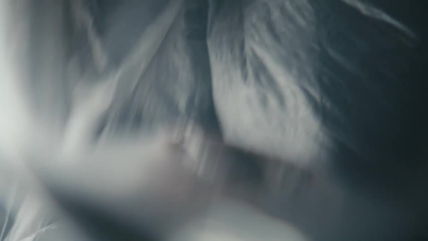 Woman moves and reaches under translucent plastic sheeting