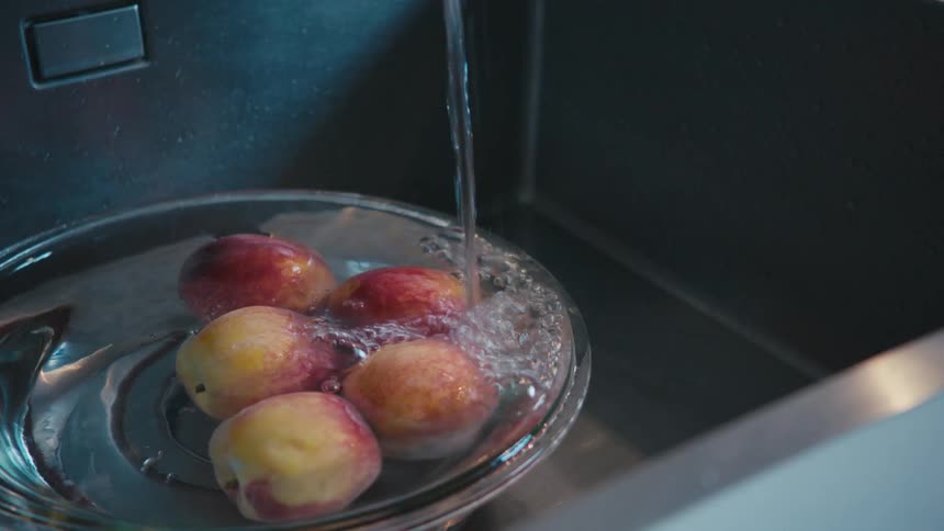 A bowl full of apples getting filled with water