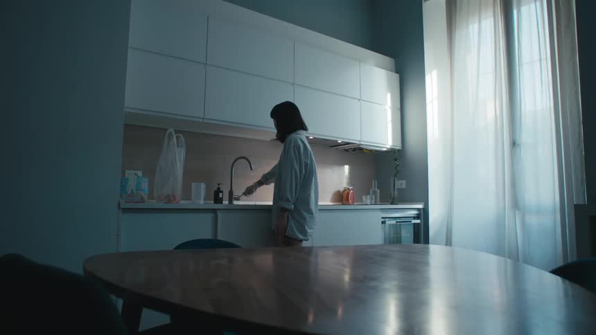 A woman turns a kitchen faucet off