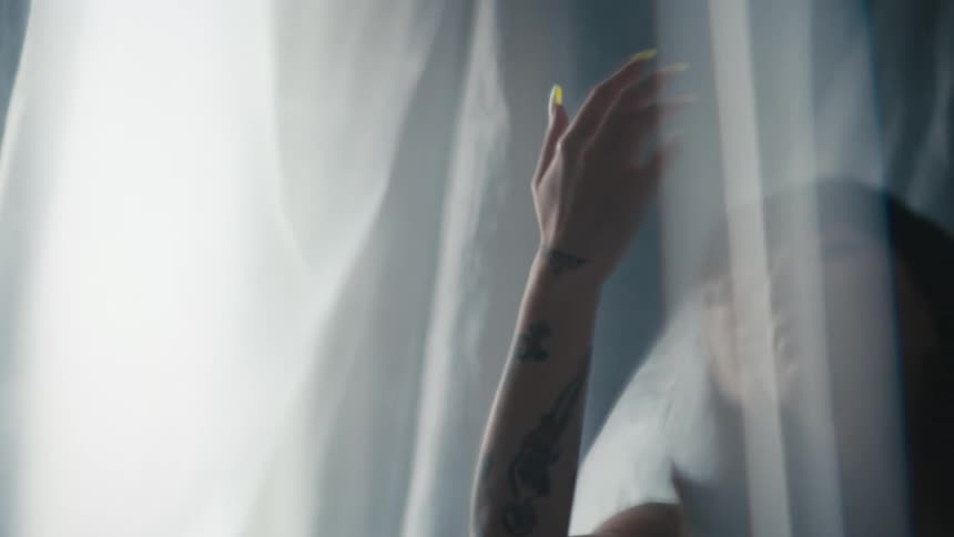 A woman in a room surrounded by plastic looking at her hand