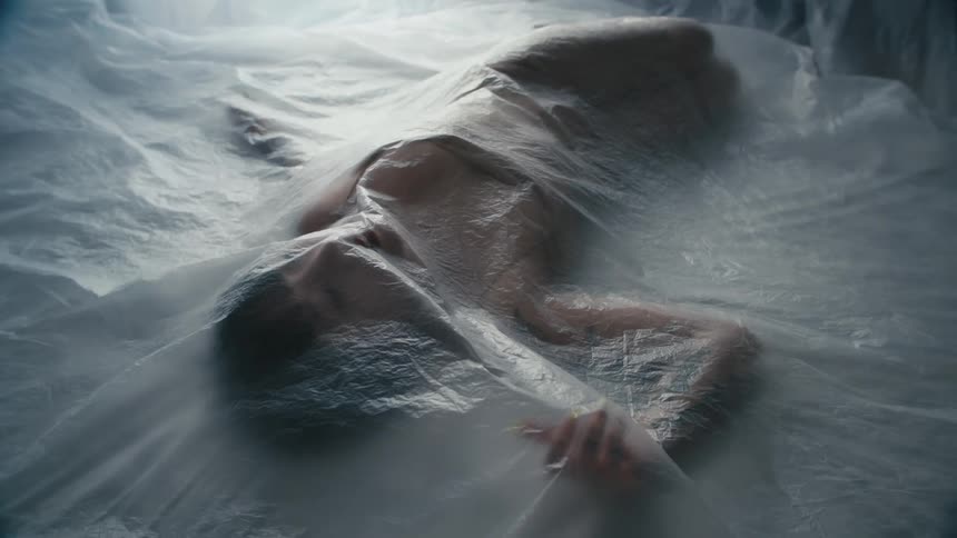 A woman laying under a sheet of plastic