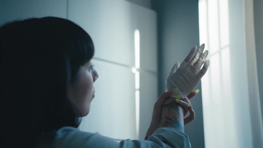 A woman looking at her hand in a glove