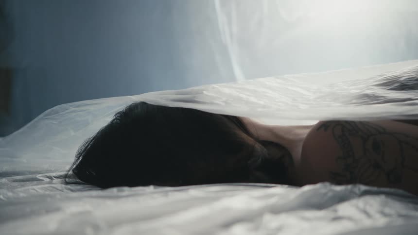 Translucent plastic sheet is pulled off woman lying motionless