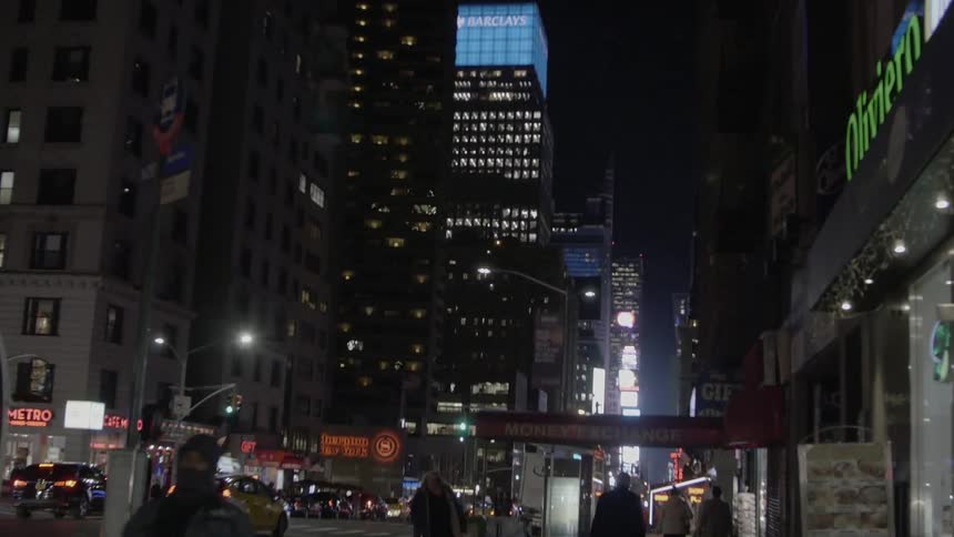 People walking on the sidewalk of a city at night