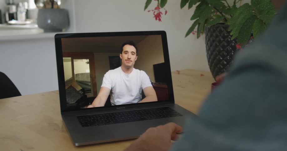 Two men talking on a video conference on a laptop