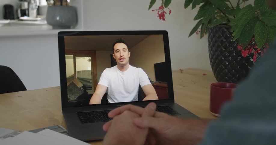 A man talking to someone on a laptop
