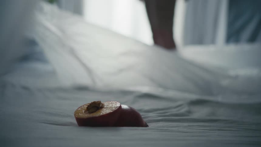 Two halves of a sliced peach lay atop a sheer piece of fabric