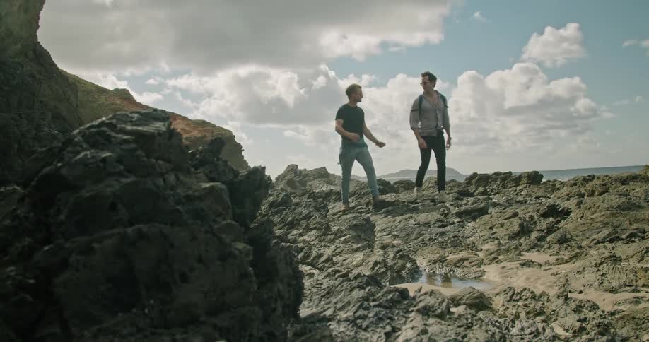 Two men hike near the edge of a cliff on a canyon