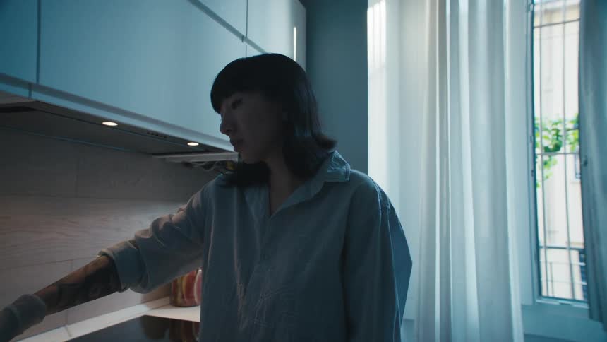 A woman in a kitchen reaches for the faucet