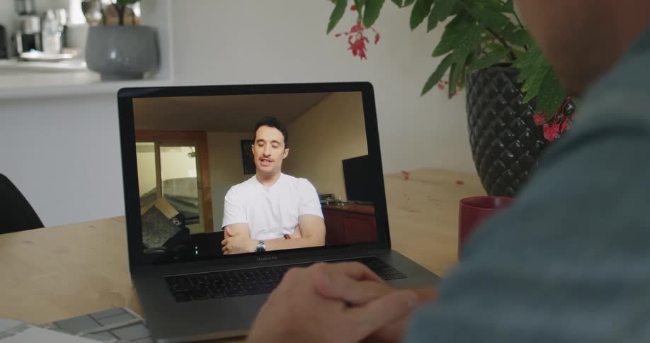 One man converses with another via a video chat on his laptop computer