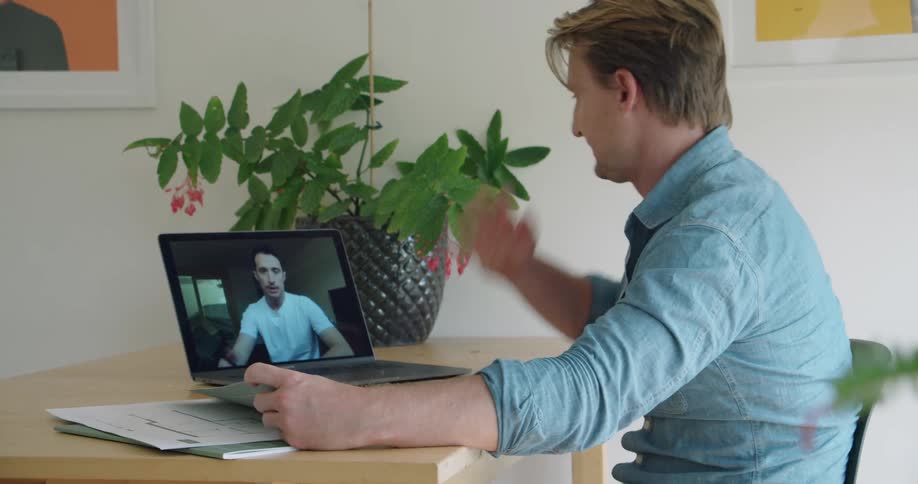 Colleagues discuss blueprints during a video call on a laptop