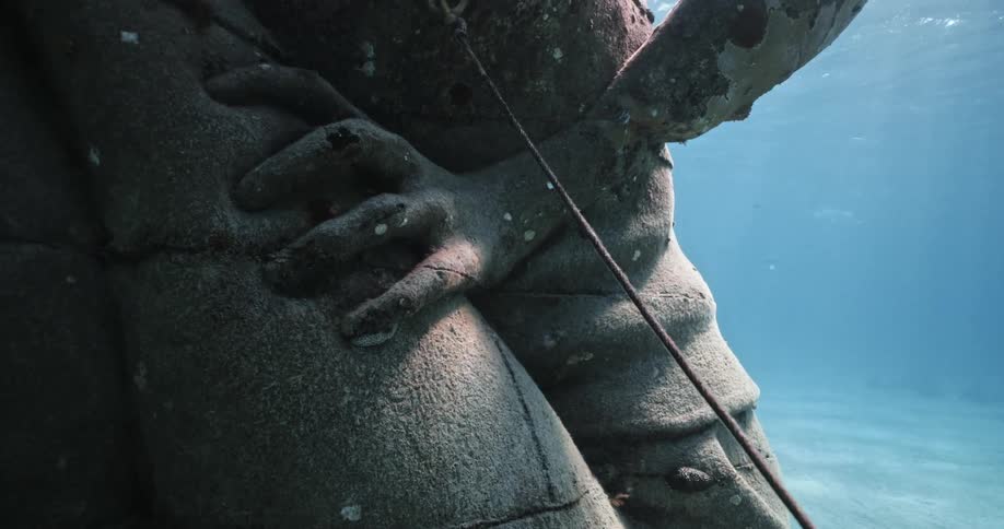 A statue underwater in the ocean with sand in the background