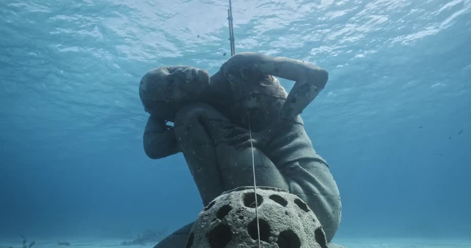 Sunlight shines on the surface above the ocean atlas underwater sculpture