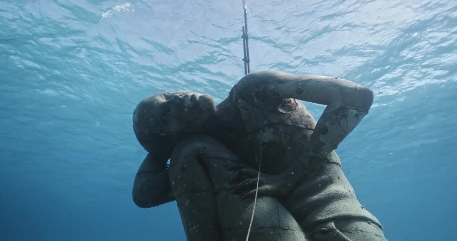 Close up of a statue submerged underwater near the coast of bahamas in the clear blue ocean water
