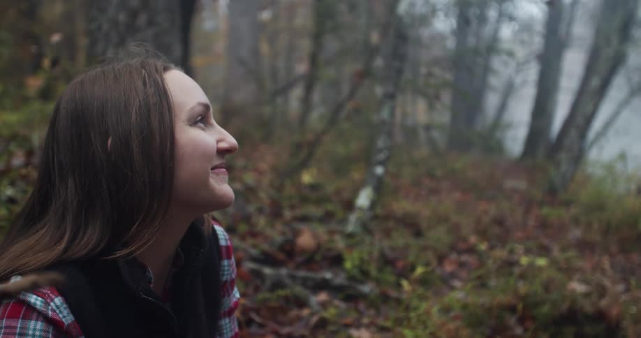 A woman sitting in a forest and smiling