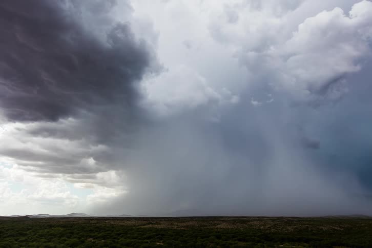 Large gray storm cloud moves across landscape obscuring mountains on the horizon