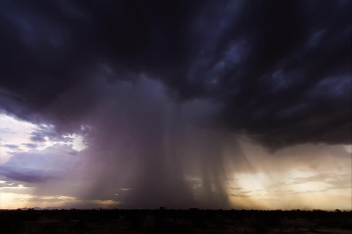 A landscape with vehicles driving by with a thunderstorm the sky and clouds in the background