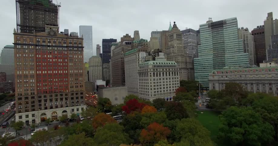 Aerial view over a park and heading into a large city