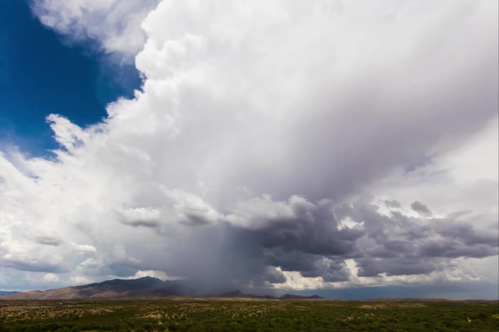 A dust storm obscures the view as it moves over a field