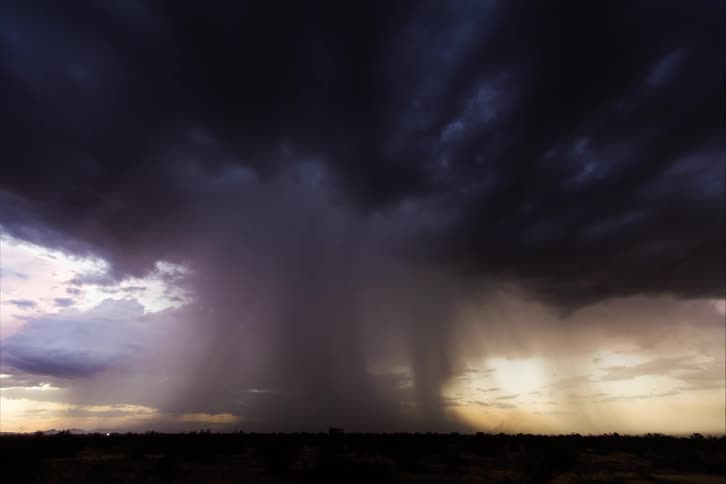 Skies darken and lightning flashes as a storm cloud moves over a field